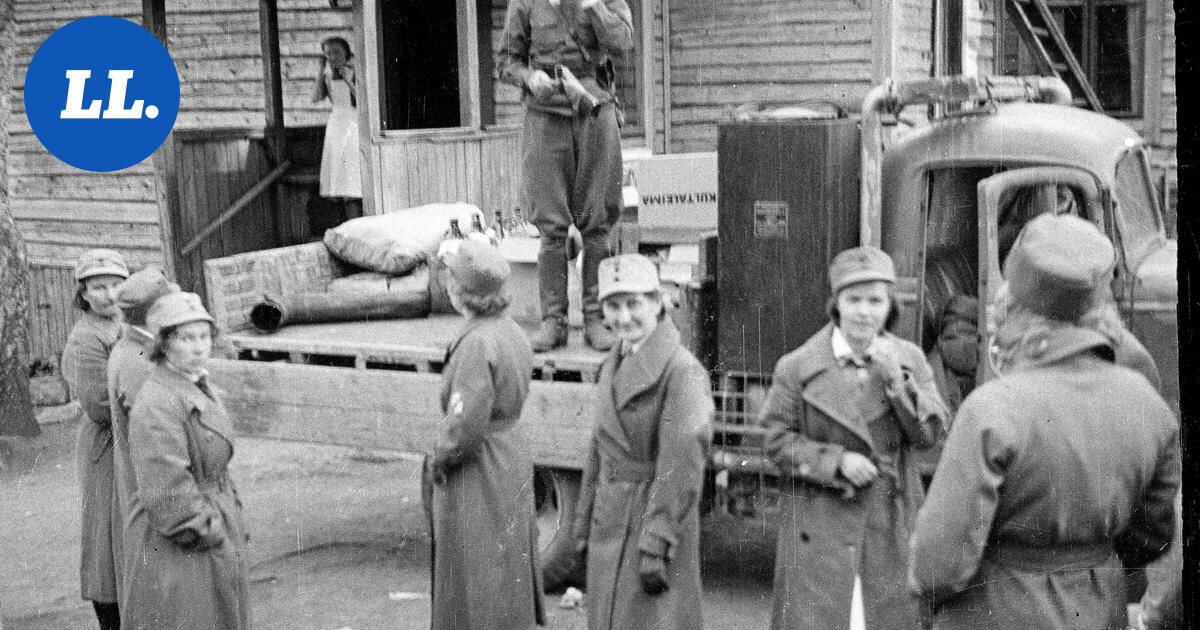 Lottia varustusten parissa Lapissa syksyllä 1944. Etualalla kuusi lottaa sotilastakeissaan, taustalla kuorma-auto ja varustelaatikko, jossa lukee KULTAEMA. Keskellä nuori lotta hymyilee kameraan. Mustavalkokuva.